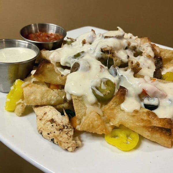 Crispy nachos topped with melted white cheese, jalapeños, black olives, and grilled chicken, served with salsa and ranch.